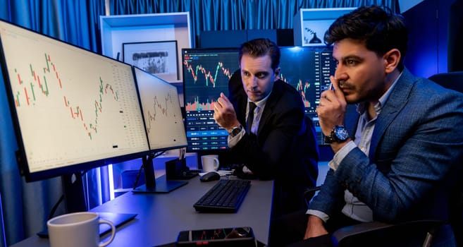 Stock exchange traders looking on high profit chart investment in panorama view, analyzing on monitor at night. Concept of discussing financial technology growth in neon light at workplace. Sellable.