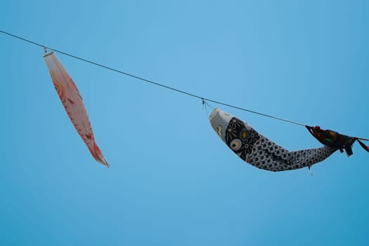 Japanese koinobori carp-shaped windsocks flying against a clear blue sky, symbolizing Children's Day.
