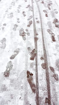 Footprints and tire tracks on a snowy surface, depicting winter travel and activity.