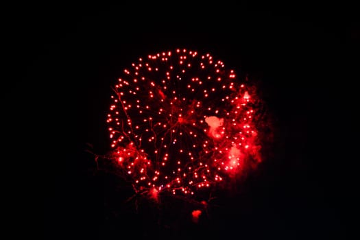 Red fireworks exploding in dark night sky, festive background concept