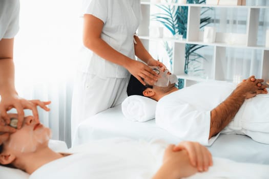 Serene daylight ambiance of spa salon, couple customer indulges in rejuvenating with luxurious cucumber facial mask. Facial skincare treatment and beauty care concept. Quiescent