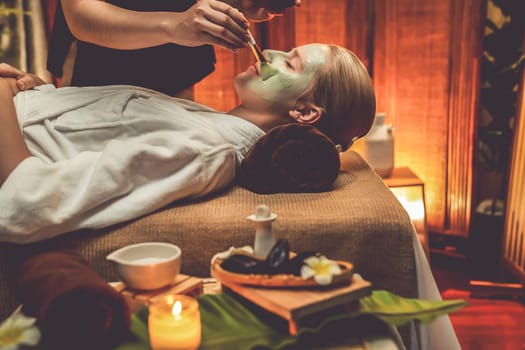 Serene ambiance of spa salon, woman customer indulges in rejuvenating with luxurious face cream massage with warm lighting candle. Facial skin treatment and beauty care concept. Quiescent