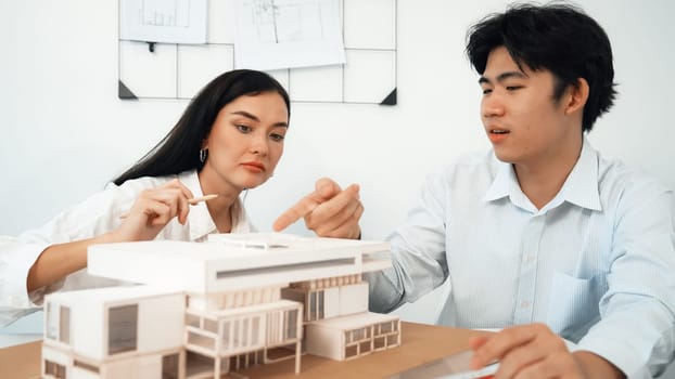 Closeup image of cooperate professional architect team working together by measuring house model on meeting table with architectural document and house model. Creative design concept. Immaculate.