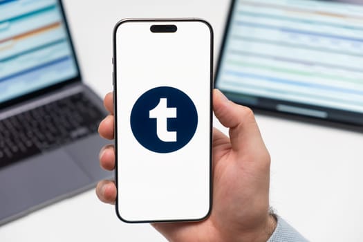 Timblr logo of social media application on the screen of smart phone in mans hand, laptop and tablet on the background, December 2023, Prague, Czech Republic