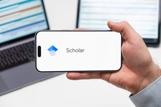 PRAGUE, CZECHIA - NOVEMBER, 2023: Google Scholar is displayed on the iPhone screen as a mans hand holds the modern smartphone
