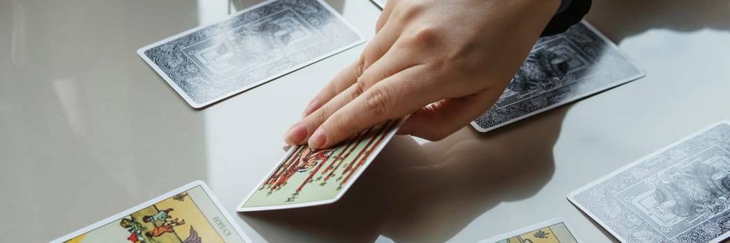 TVER, RUSSIA - FEBRUARY 11, 2023. Tarot cards, Tarot card divination, esoteric background. A woman makes a layout on the cards at the table. Divination, predictions on tarot cards