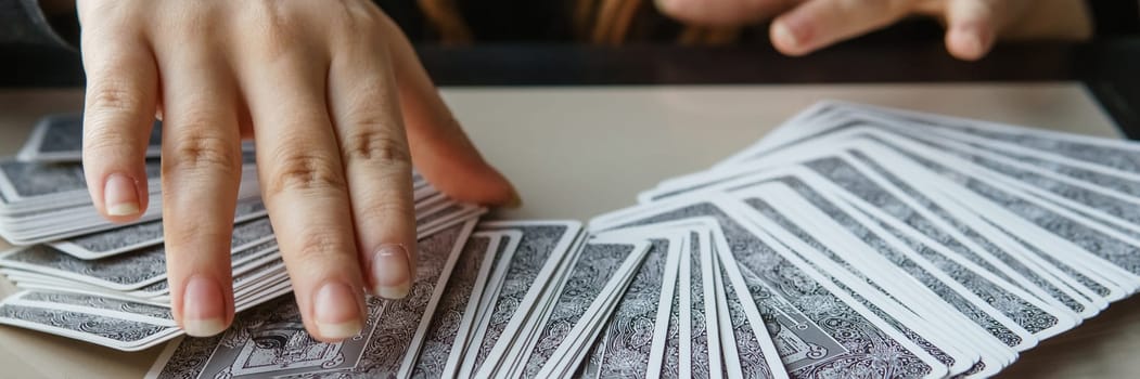 TVER, RUSSIA - FEBRUARY 11, 2023. Tarot cards, Tarot card divination, esoteric background. A woman makes a layout on the cards at the table. Divination, predictions on tarot cards