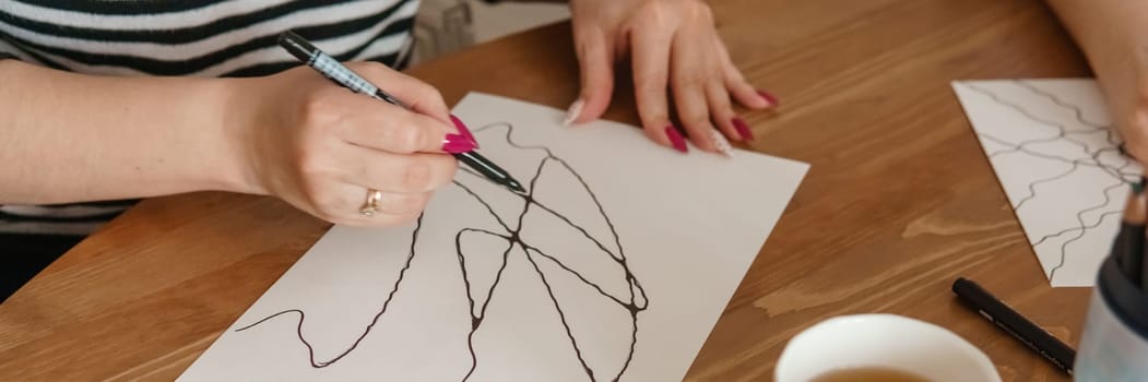 TVER, RUSSIA - FEBRUARY 25, 2023: Woman draws neurographics at table at a psychological session, neurographic pencil drawing to remove restrictions, art therapy.