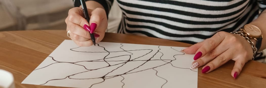 TVER, RUSSIA - FEBRUARY 25, 2023: Woman draws neurographics at table at a psychological session, neurographic pencil drawing to remove restrictions, art therapy.