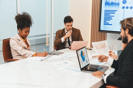 Professional businesspeople analysis financial statistic at meeting. Diverse business team working together to brainstorm, plan, share marketing idea on table with laptop ,book ,document. Ornamented.