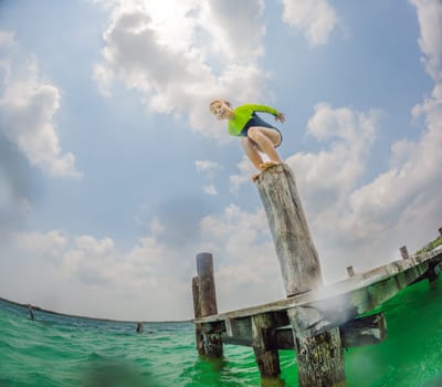 Joyful boy jumps into a turquoise lake in Mexico.