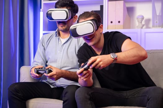 Buddy friend gamers playing video game using joysticks and VR headset of virtual technology in reality in studio room with neon blue light. Comfy living indoor with cheerful fighting winner. Sellable.