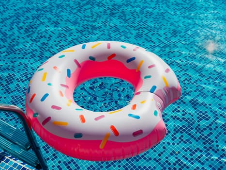A toy rubber bitten donut with caramel sprinkles next to the pool railing.