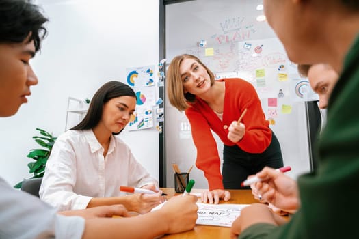 Creative happy business team brainstorming and sharing idea by using mind map and graphic graph while young beautiful project manager pointing at important point at business meeting. Immaculate.