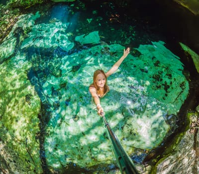 Woman immersed in the enchanting beauty of a Mexican cenote, surrounded by crystal-clear waters and captivating natural formations.