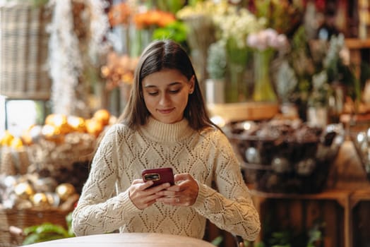 In the decor store, a beautiful young woman is seen with her phone. High quality photo