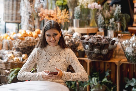 In the decor store, a young woman is seen holding her phone. High quality photo