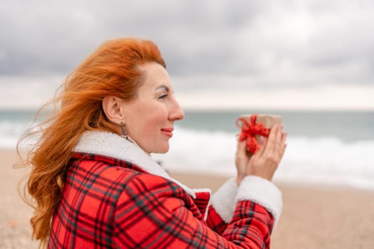 Lady in plaid shirt holding a gift in his hands enjoys beach. Coastal area. Christmas, New Year holidays concep.