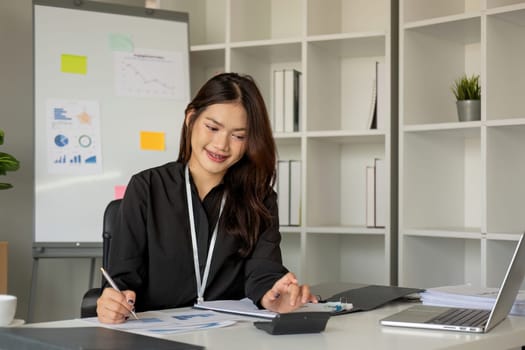 Business woman using calculator and laptop for do math finance on wooden desk in office and business working background, tax, accounting, statistics and analytic research concept.