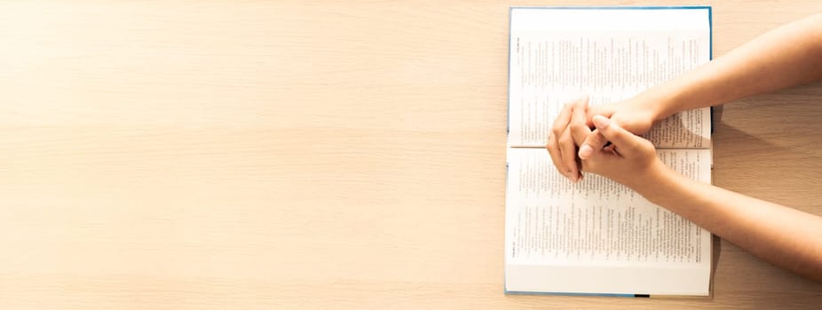 Female prayer folding hand on holy bible book on wooden church table. Concept of hope, religion, faith, christianity praying for love and god blessing. Warm and brown background.Top view. Burgeoning.