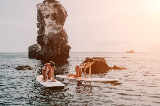 Woman sup yoga. Middle age sporty woman practising yoga pilates on paddle sup surfboard. Female stretching doing workout on sea water. Modern individual hipster outdoor summer sport activity