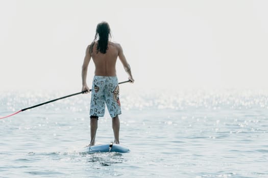 Man Sea Sup. Strong athletic man learns to paddle sup standing on board in open sea ocean on sunny day. Summer holiday vacation and travel concept. Aerial view. Slow motion.