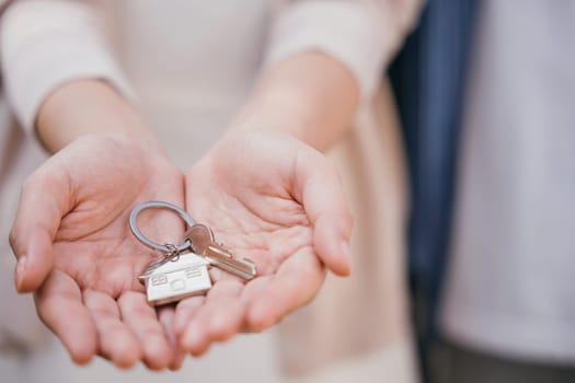 Landlord's hand presents keys for a new house. Symbolizes investment tenant security and real estate ownership. Close-up view denotes successful property deal. Give me the keys