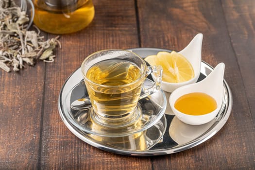 Dried sage tea in glass cup on wooden table