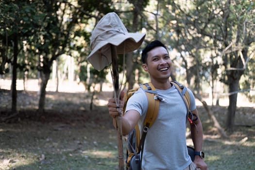 Portrait of a happy smiling Asian tourist, 30-35 years old, backpacking in a national park. asian male tourist enjoying his hiking trip Nature activities, holidays, outdoor hobbies..