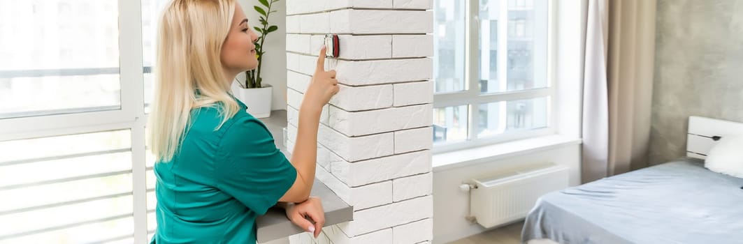 Close Up Of Woman Adjusting Wall Mounted Digital Central Heating Thermostat Control At Home.