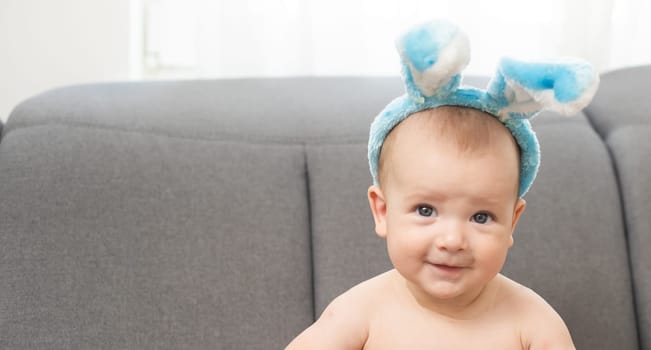 happy caucasian baby girl six months old wearing bunny ears headband.