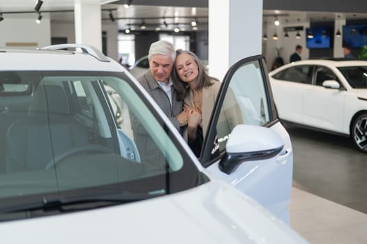 An elderly Caucasian couple chooses a new car at a car dealership