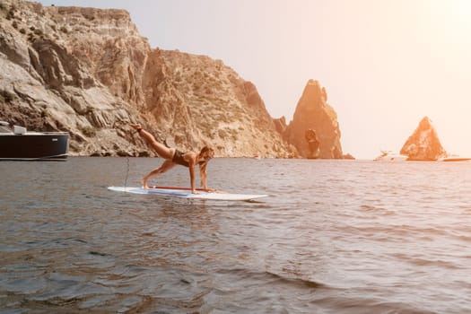 Close up shot of beautiful young caucasian woman with black hair and freckles looking at camera and smiling. Cute woman portrait in a pink bikini posing on a volcanic rock high above the sea