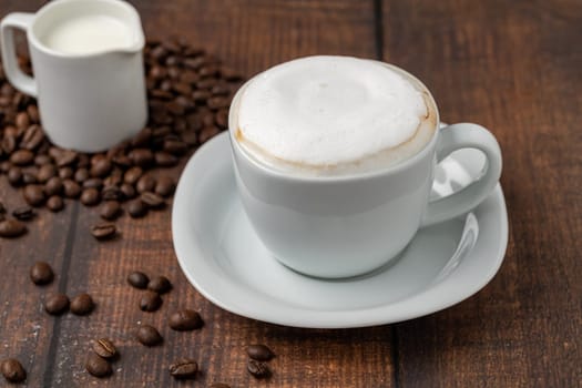 Cappuccino coffee in a white porcelain cup on a wooden table