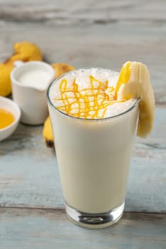 Milk with honey and banana in glass glass on wooden table