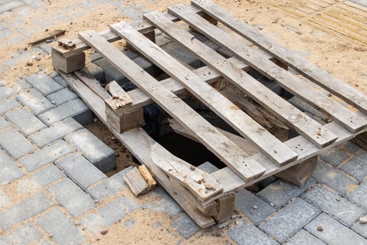 The hole in the asphalt is covered with a wooden pallet