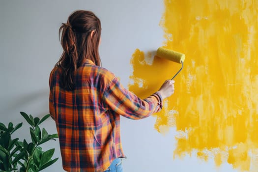 The girl gives the wall a bright yellow tint using a paint roller.