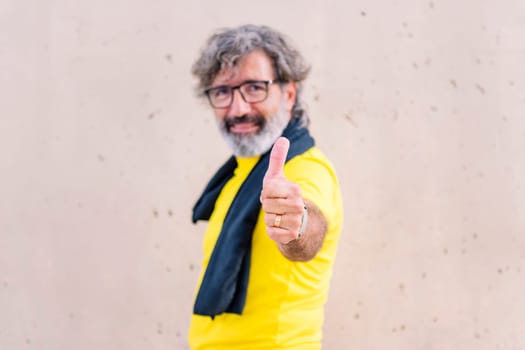 senior sports man smiling happy with with thumb up looking at camera, concept of active and healthy lifestyle on the middle age, selective focus on hand, copy space for text