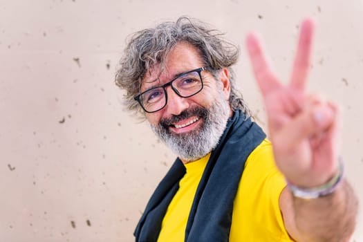 senior sports man with glasses smiling happy doing victory sign with hand looking at camera, concept of active and healthy lifestyle on the middle age, copy space for text