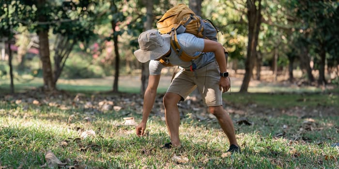 Young man backpacker traveling alone in forest. Attractive male traveler walking in nature wood during holiday vacation trip.