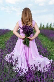 A bouquet of lavender and a girl in a purple dress, a photo shoot of a girl in a lavender field, back view of the girl.