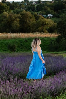 a girl in a blue long sundress on a lavender field, a brunette girl poses for a photo.