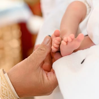 The priest performs the rite of baptism of the child and anoints the leg with holy myrrh, the sacrament of Christian baptism.