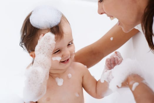 Baby, bath and mother laughing in a bathroom with cleaning, foam and help with love and support. Care, mom and young child with soap in a home with bonding and washing for wellness and hygiene.