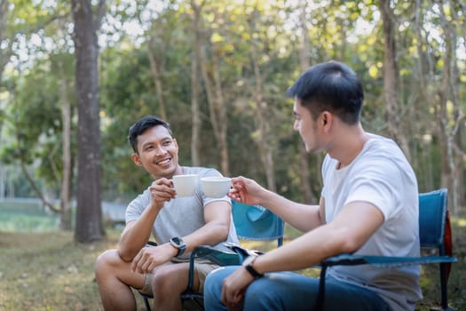 Male gay couple asian traveling with tent camping outdoor and various adventure lifestyle hiking active summer vacation. drinking coffee and talking together.