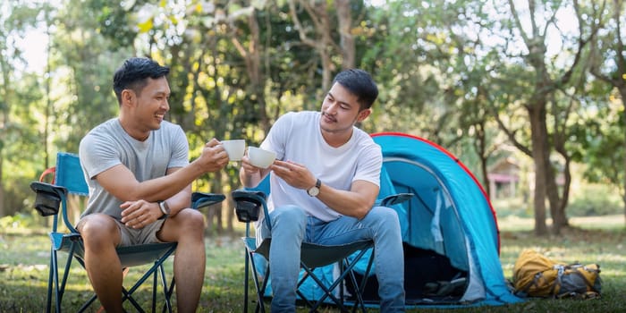 Male gay couple asian traveling with tent camping outdoor and various adventure lifestyle hiking active summer vacation. drinking coffee and talking together.