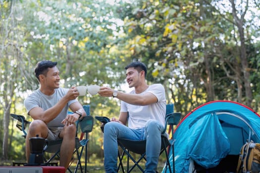 Male gay couple asian traveling with tent camping outdoor and various adventure lifestyle hiking active summer vacation. drinking coffee and talking together.