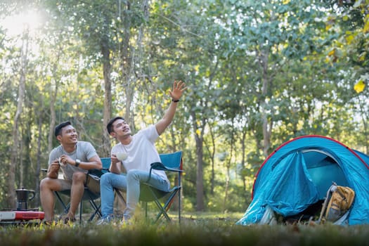 Male gay couple asian traveling with tent camping outdoor and various adventure lifestyle hiking active summer vacation. drinking coffee and talking together.