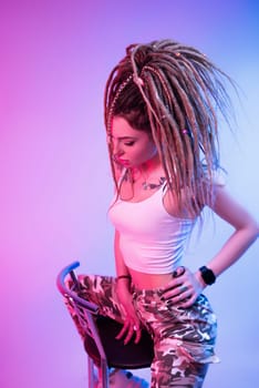 the cool girl with braided dreadlocks on her head in neon light on a light background