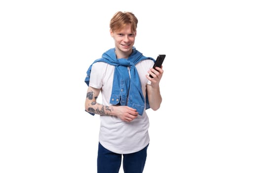 young friendly handsome european man with red hair and a tattoo on his arms writes a message on the phone.